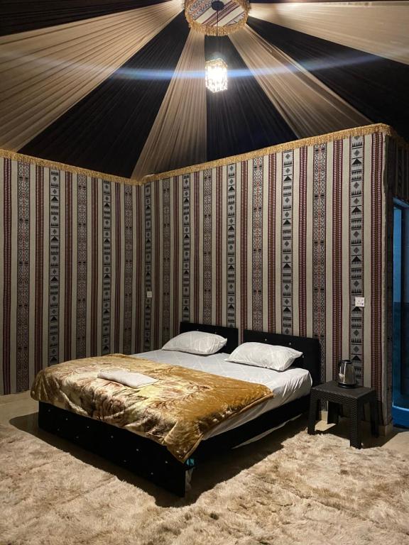 a bed in a room with a wall with a ceiling at WADi RUM ALi CAMP in Wadi Rum