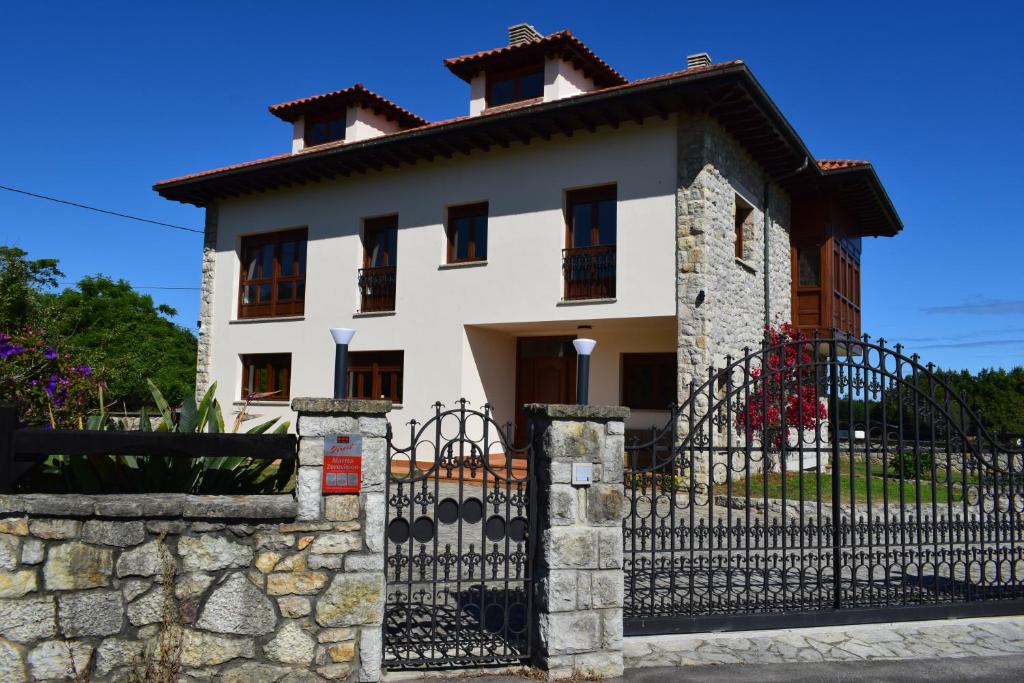 una gran casa blanca con una valla negra en Villa El Martín en Naves