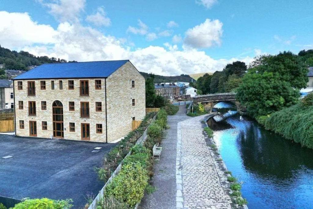 a building next to a river with a bridge at Mill Bank Apartment in Todmorden