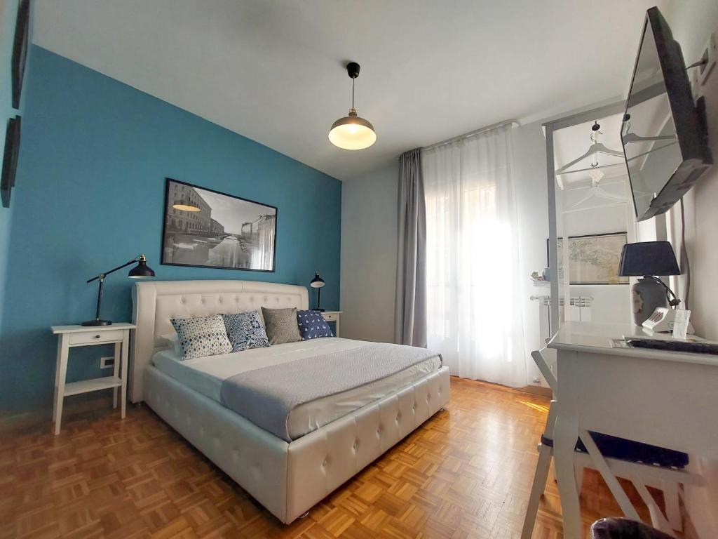 1 dormitorio con 1 cama con paredes azules y escritorio en MyWay Trieste Rooms, en Trieste