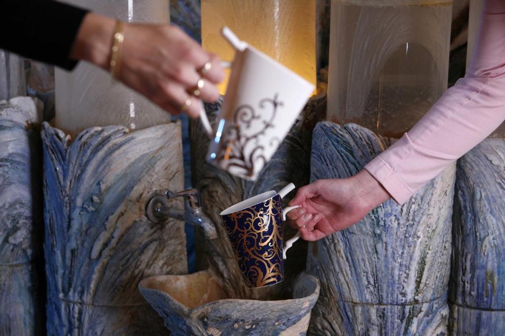 a person holding a cup in front of a vase at Spa Hotel Imperial in Karlovy Vary