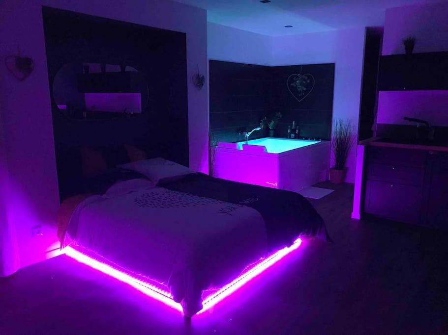 Un dormitorio con una cama con luces moradas. en Le Cocon du bourg d’Agon en Agon Coutainville