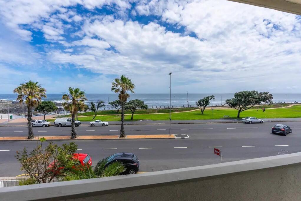 uma vista para um parque de estacionamento com palmeiras e o oceano em Beachfront Luxury Family Escape em Cidade do Cabo
