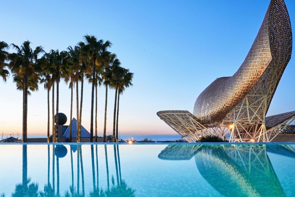a view of a resort with a pool and palm trees at Hotel Arts Barcelona in Barcelona