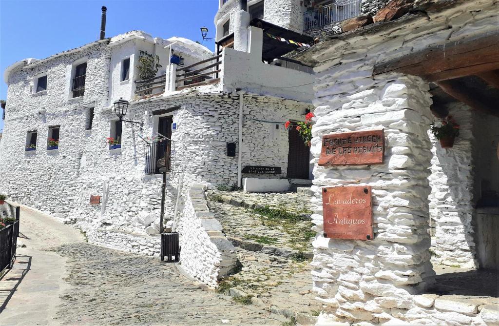 a stone building with a sign on the side of it at La Casa de la Bombilla Verde in Trevélez