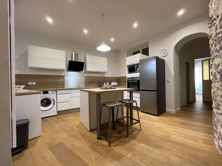 une cuisine avec des placards blancs et un îlot avec des tabourets de bar dans l'établissement T4 atypique plein centre ville classé 3 étoiles, à Sète