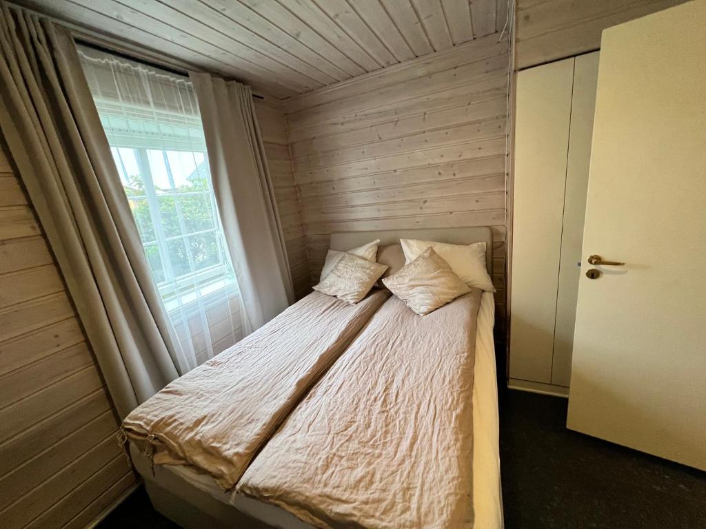 a small bedroom with a bed with a window at Cosy and well-equipped apartment with free parking in Trondheim