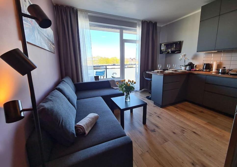 a living room with a blue couch and a kitchen at Stylish apartment with parking & spacious balcony in Rīga