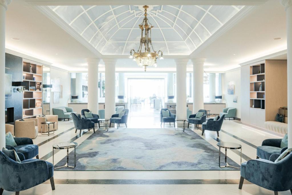 une grande salle d'attente avec des chaises et un lustre dans l'établissement Grand Hotel Suisse Majestic, Autograph Collection, à Montreux