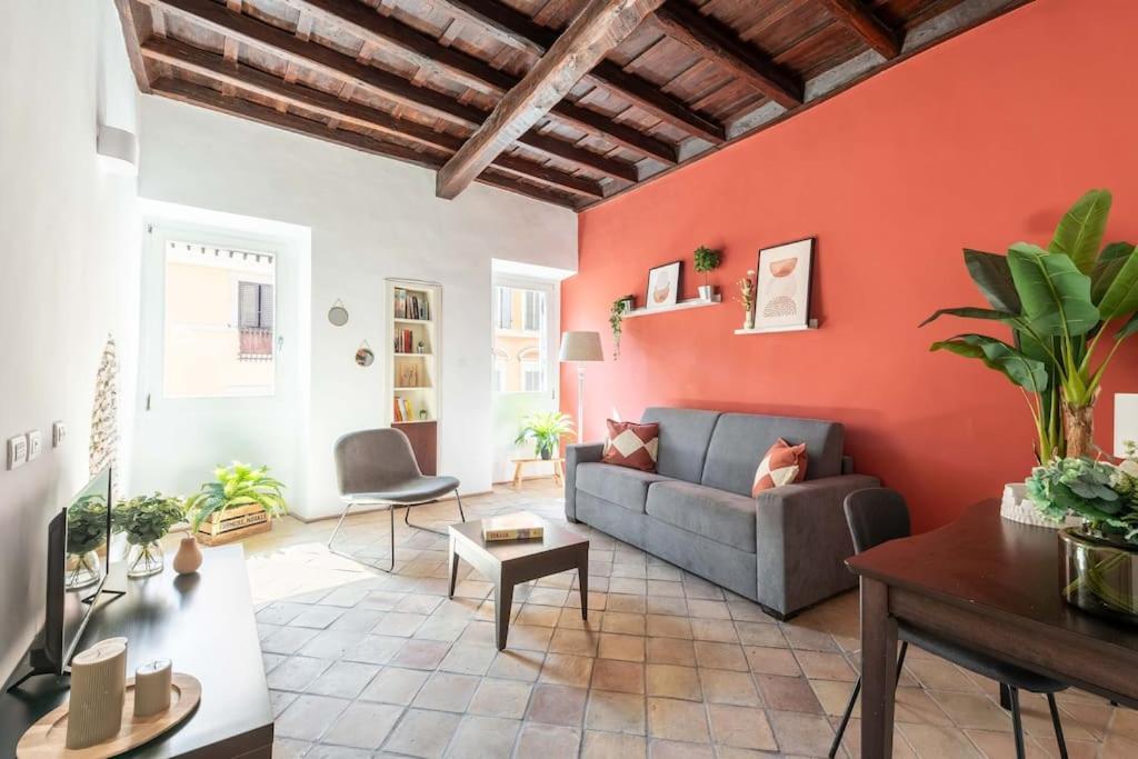 uma sala de estar com um sofá e uma parede laranja em Maison Leonardo al Colosseo em Roma