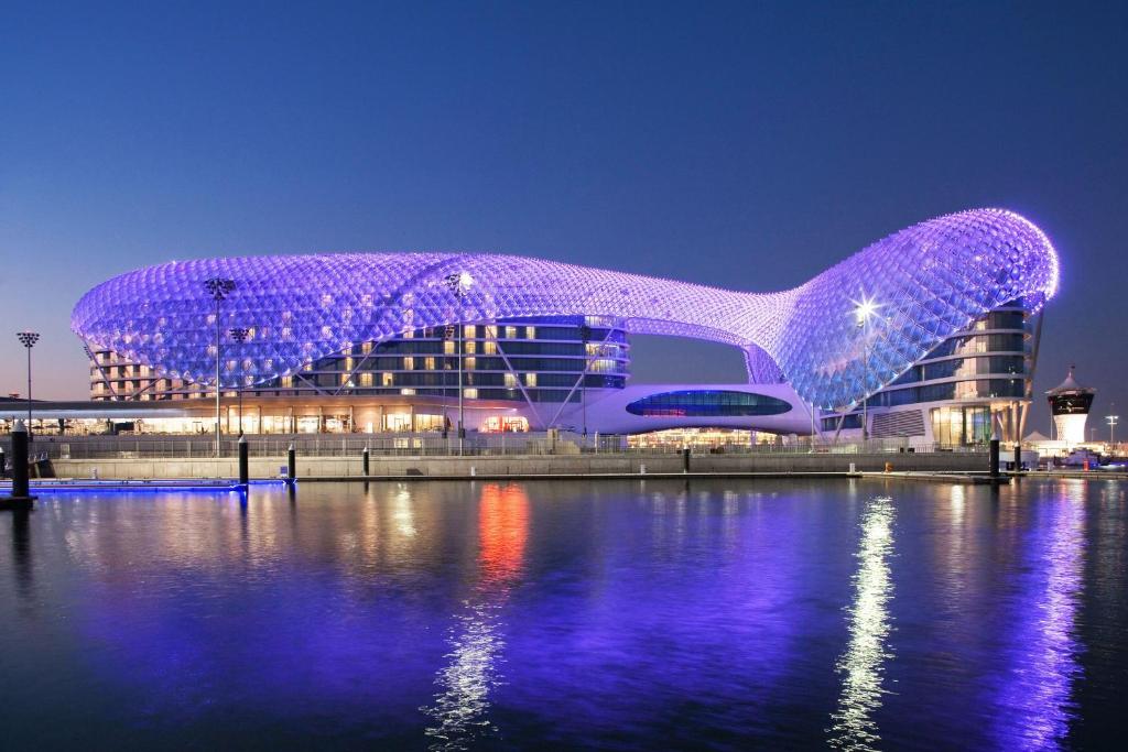 a building covered in purple lights next to a body of water at W Abu Dhabi - Yas Island in Abu Dhabi