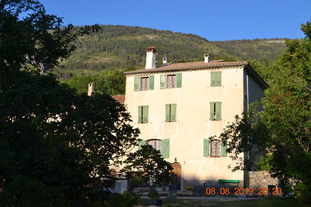 uma grande casa branca com uma montanha ao fundo em Pays du Verdon , étape, séjour fraîcheur dans maison de caractère em La Bastide