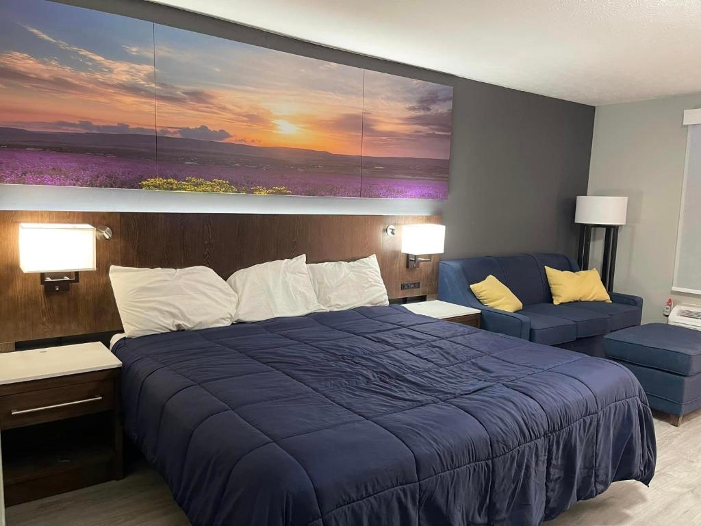 Un dormitorio con una gran cama azul y un sofá en Luxor Inn & Suites, a Travelodge by Wyndham, en Elkins