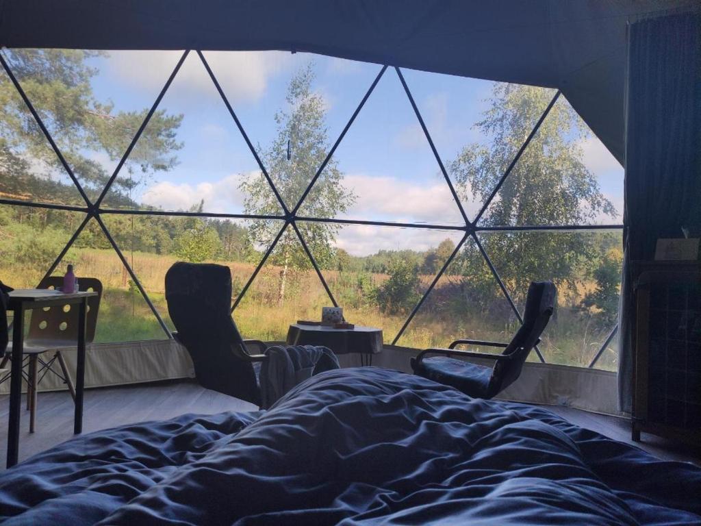 a bedroom with a bed and chairs and a large window at Glamping Drzwi Do Lasu in Supraśl