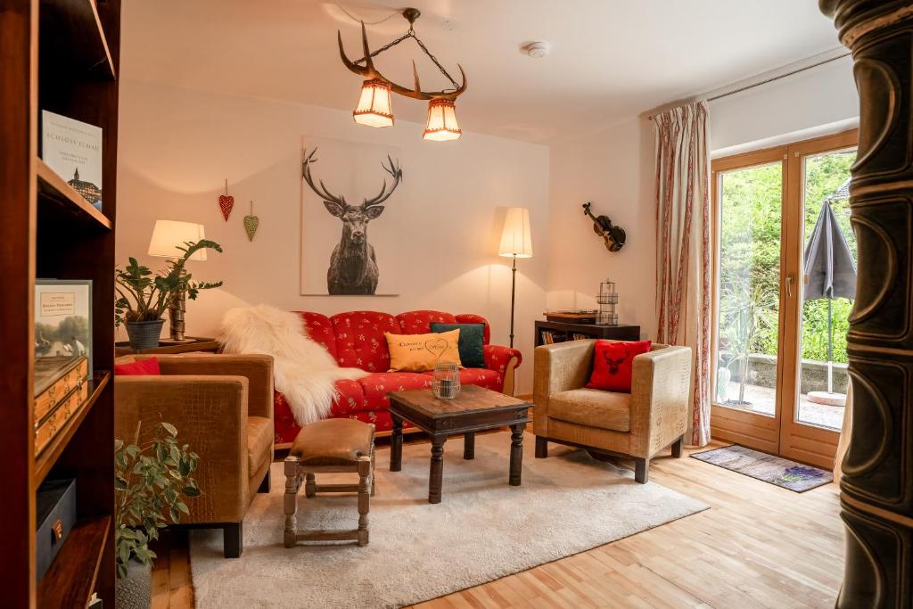 ein Wohnzimmer mit einem roten Sofa und Stühlen in der Unterkunft Engelsherz in Mittenwald