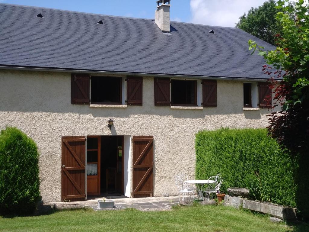 dom z brązowymi drzwiami i stołem na dziedzińcu w obiekcie Gîte de la Séoube w mieście Campan