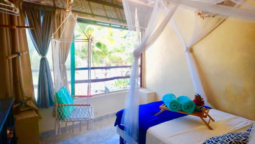 1 dormitorio con cama con dosel y ventana en Casa Lilo Mahahual - privat house en Mahahual