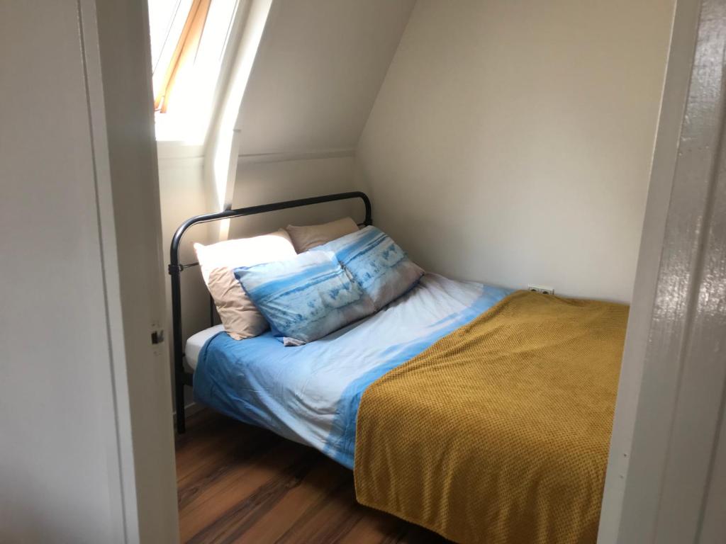Dormitorio pequeño con cama con almohadas en Logeren bij de bakker, en Schiermonnikoog