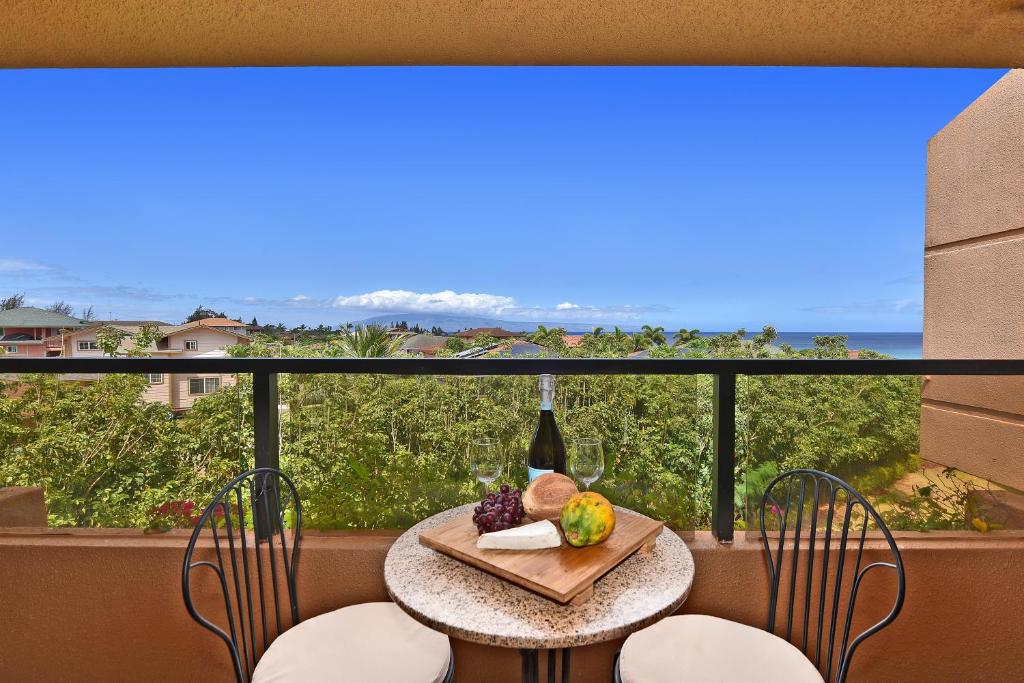a table with a bottle of wine and fruit on a balcony at Kahana Villa E601 in Kahana
