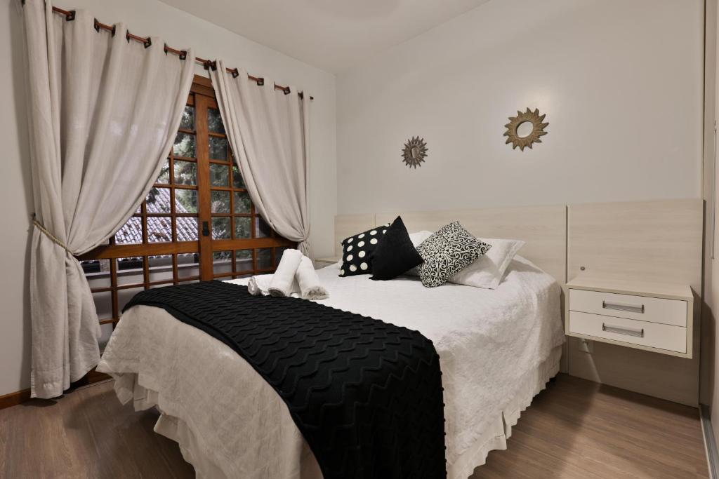 a bedroom with a bed with a black blanket and a window at Apartamento de 1 quarto in Gramado