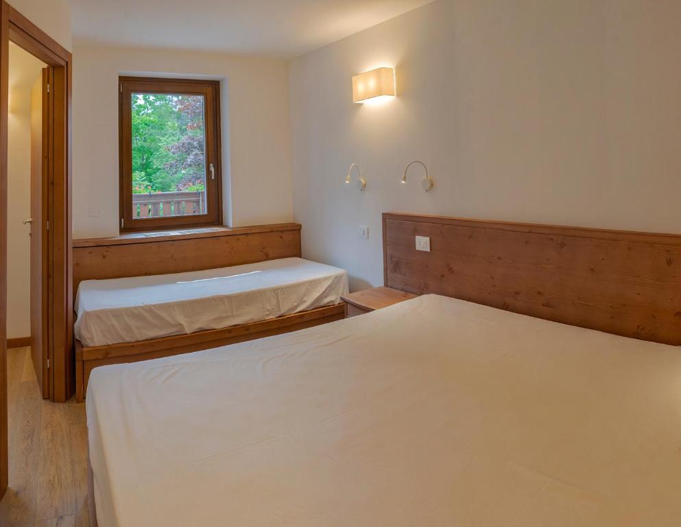 una camera con due letti e una finestra di Appartamento con terrazza di mq 40 con vista Pale di San Martino a San Martino di Castrozza