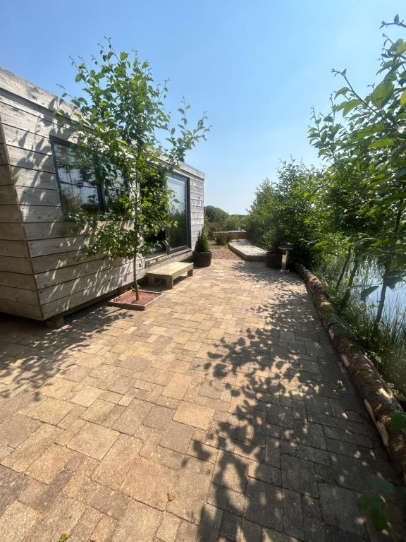 a brick walkway next to a building with a window at Secluded Lakeside Off Grid Cabin with Outdoor Bath in Rhosneigr