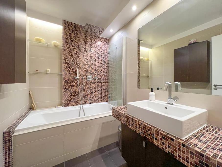 a bathroom with a white tub and a sink and a bath tub at Full apt - Top floor - Eiffel Tower Panoramic View in Issy-les-Moulineaux