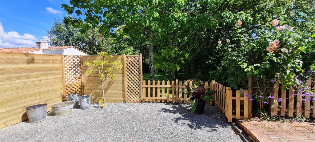 a wooden privacy fence with a tree in a yard at Au ptit Manoir in Montbert