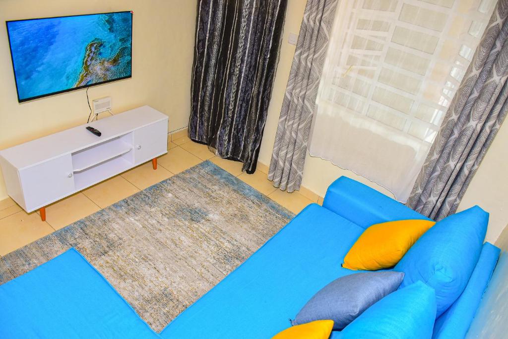 Sofá azul en la sala de estar con ventana en Karibu Place Kamakis- Opp Greenspot Gardens, en Ruiru