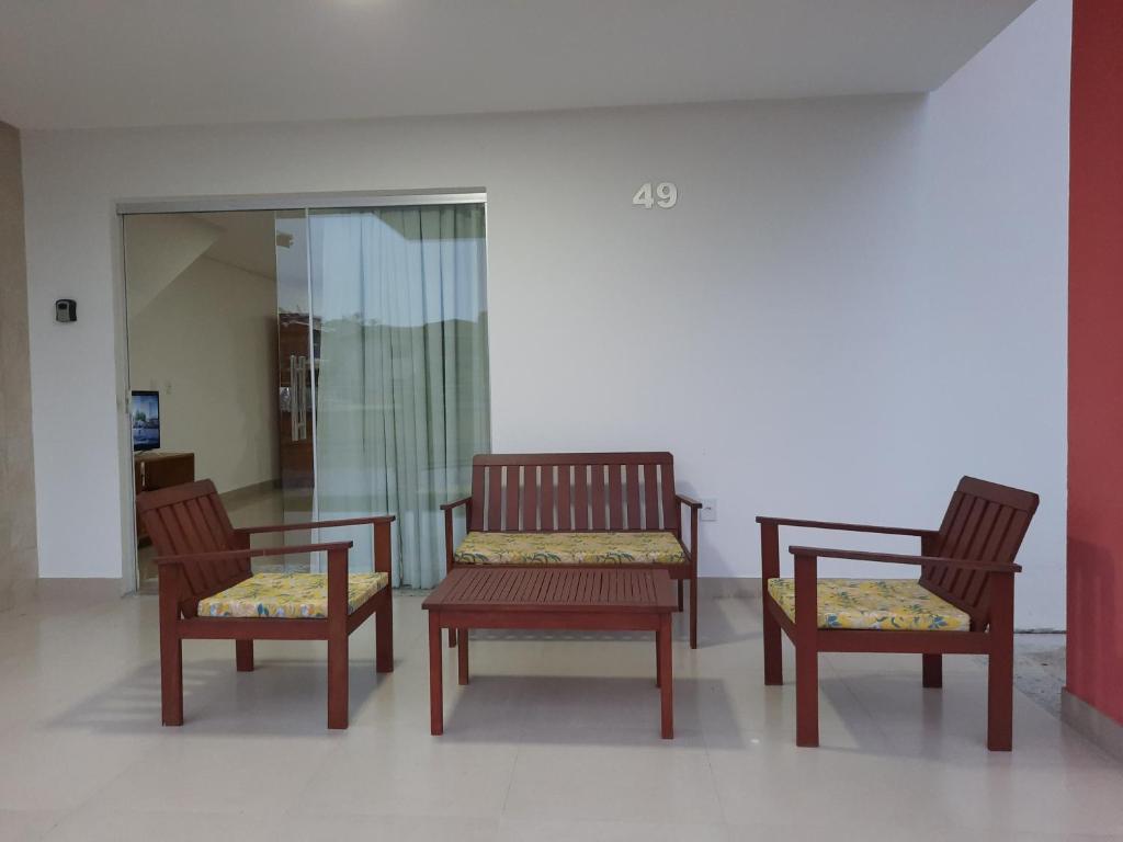 a group of three wooden chairs sitting in a room at Casa do Mutá in Porto Seguro