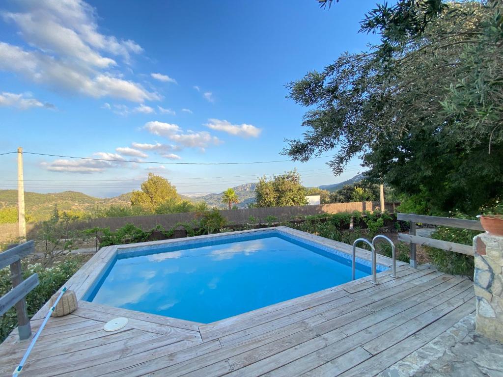 a swimming pool with a wooden deck and a poolvisor at Finca es Born - vistas panorámicas in Esporles