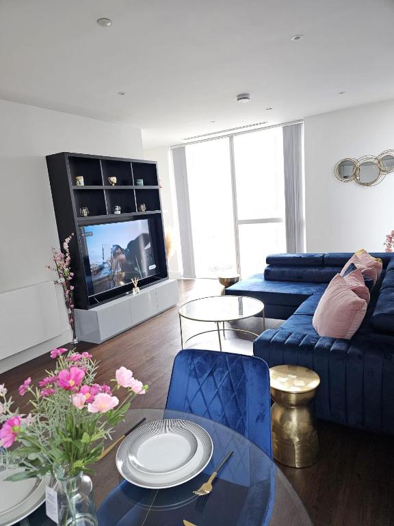 sala de estar con sofá azul y TV en 2 bed Luxurious apartments Canary Wharf en Londres