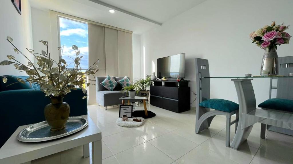 uma sala de estar com um vaso de flores sobre uma mesa em CB Apto cómodo e impecable con Aire Acondicionado em Neiva
