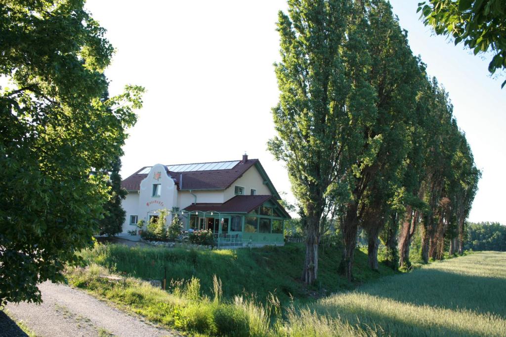 ein weißes Haus auf einem Hügel mit Bäumen in der Unterkunft Rosenhotel - Serviced Apartments in Zwentendorf