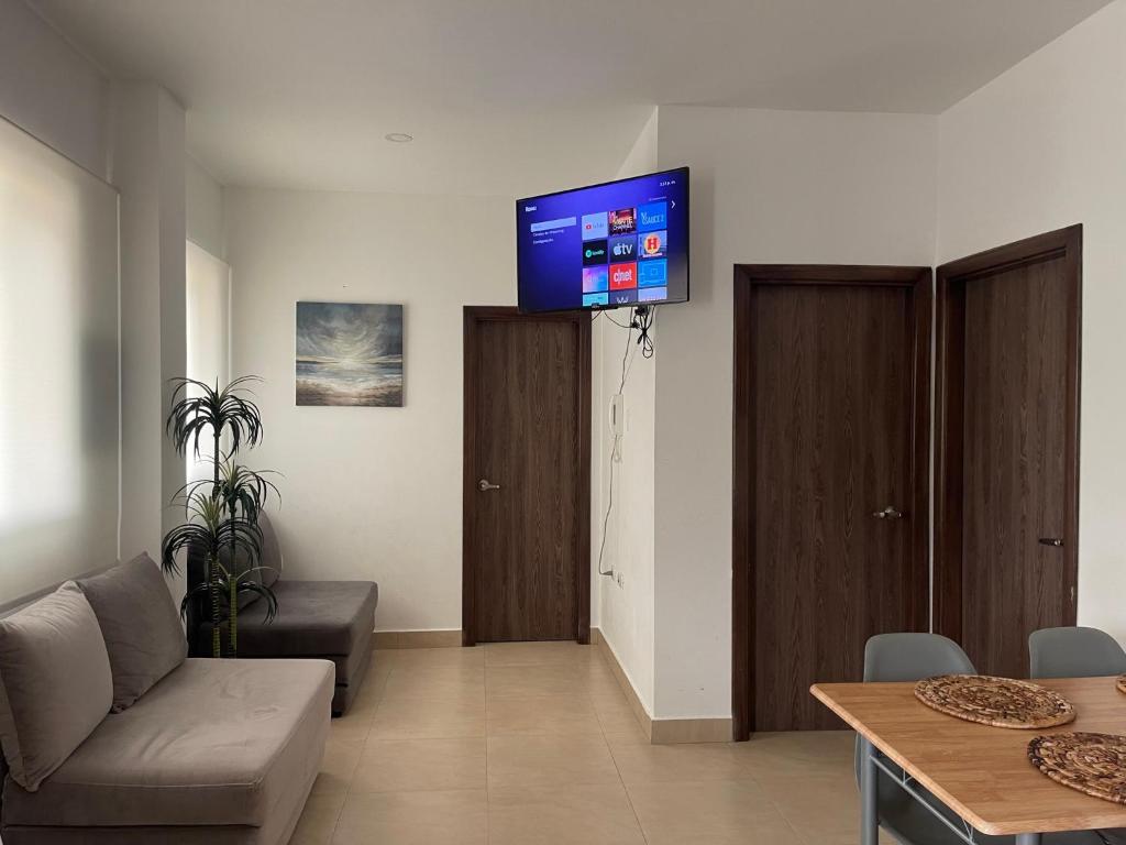 - un salon avec un canapé et une télévision murale dans l'établissement Hermoso hogar con bbq y piscina en Punta Blanca, à Punta Blanca