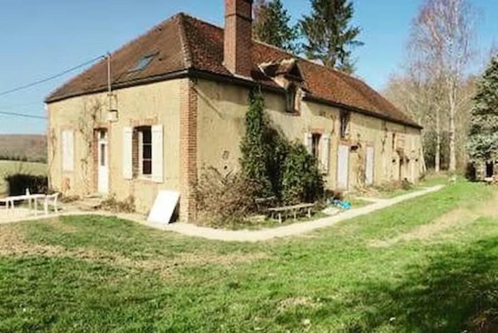 una vieja casa de ladrillo con un patio de hierba delante de ella en Logement studio dans un coin paradisiaque 