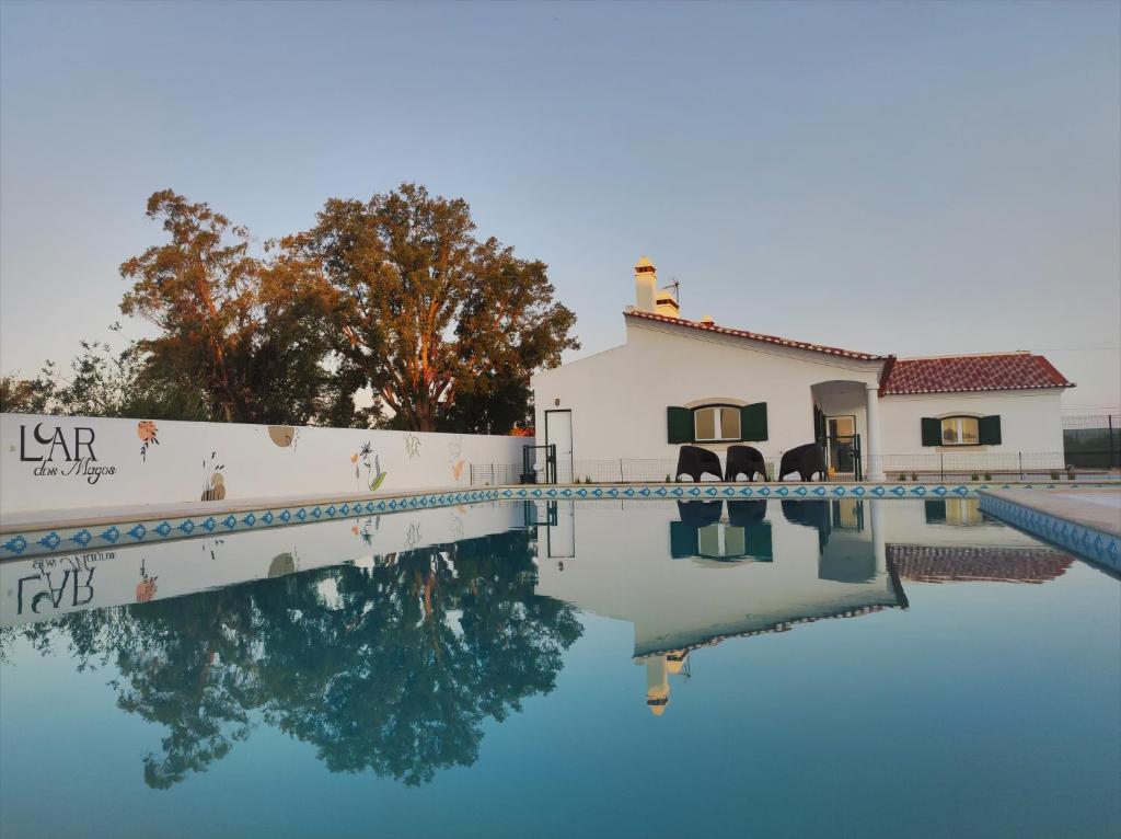 een huis en een zwembad met reflectie in het water bij Luar dos Magos in Salvaterra de Magos