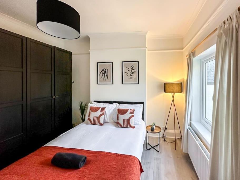 a bedroom with a large bed with a red blanket at Luxe & Stylish 1 Bed Flat in London