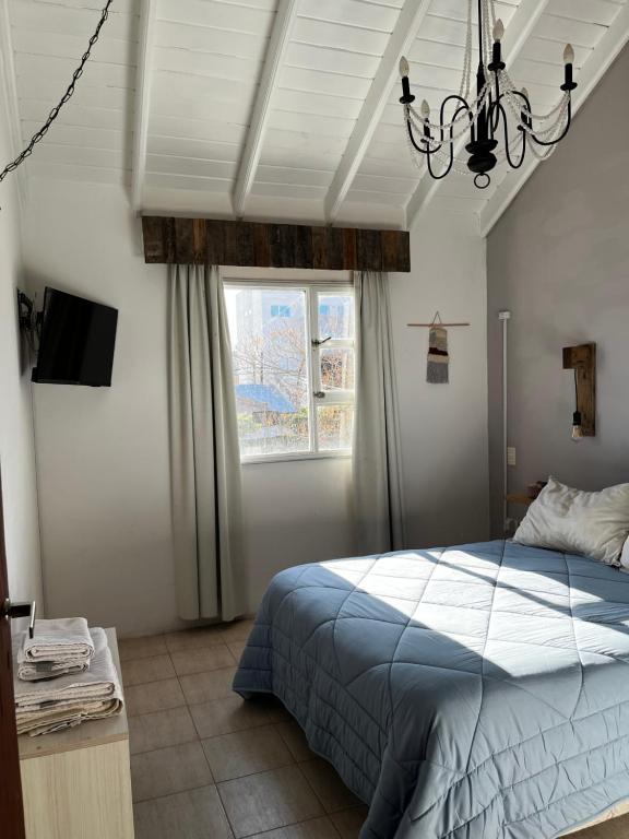a bedroom with a bed and a window and a chandelier at Tehuelches del sur in Puerto Madryn
