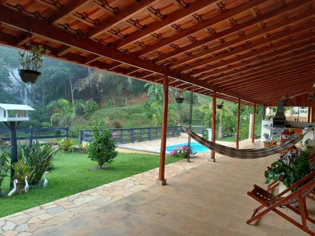 eine Terrasse mit einer Hängematte und einem Pool in der Unterkunft Sítio Olho de Boneca in Itamonte