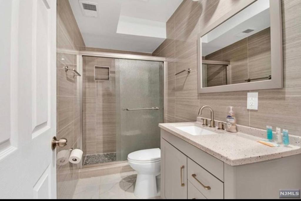 uma casa de banho com um WC, um chuveiro e um lavatório. em Cozy Inspired Studio Apartment em Newark