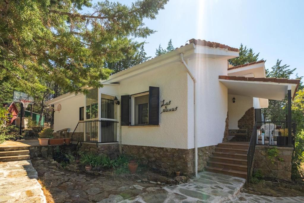 a small white house with a porch and stairs at Casa Rural Los Olivos de Robledo de Chavela in La Estación