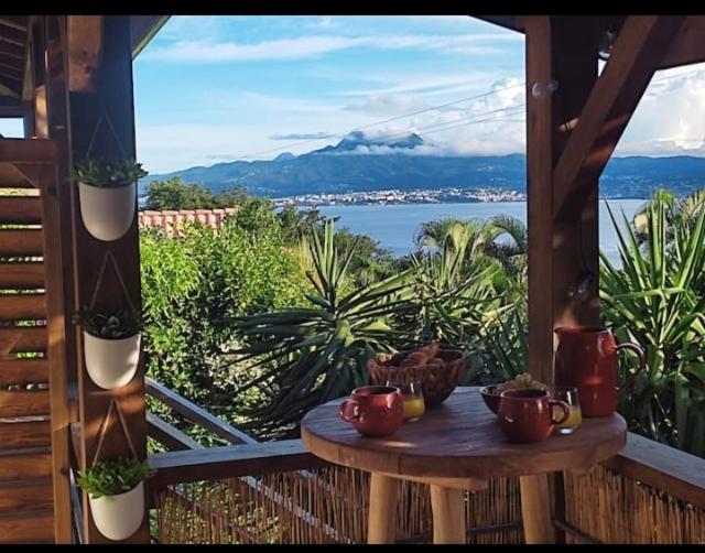 een tafel op een veranda met uitzicht op het water bij Coin de paradis proche de la plage in Les Trois-Îlets