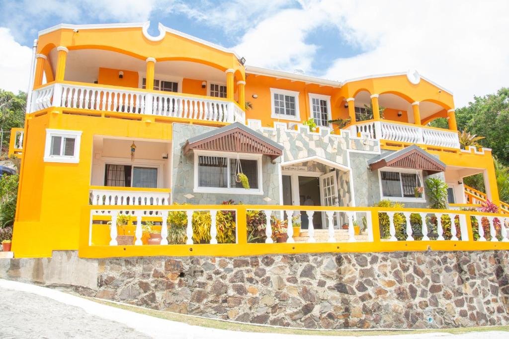 a large yellow house on a stone wall at Mountain View Apartments in Gros Islet