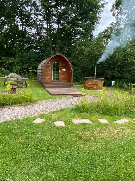 a small cabin in the grass with a grill at Country pod with wood fired hot tub in Clodock