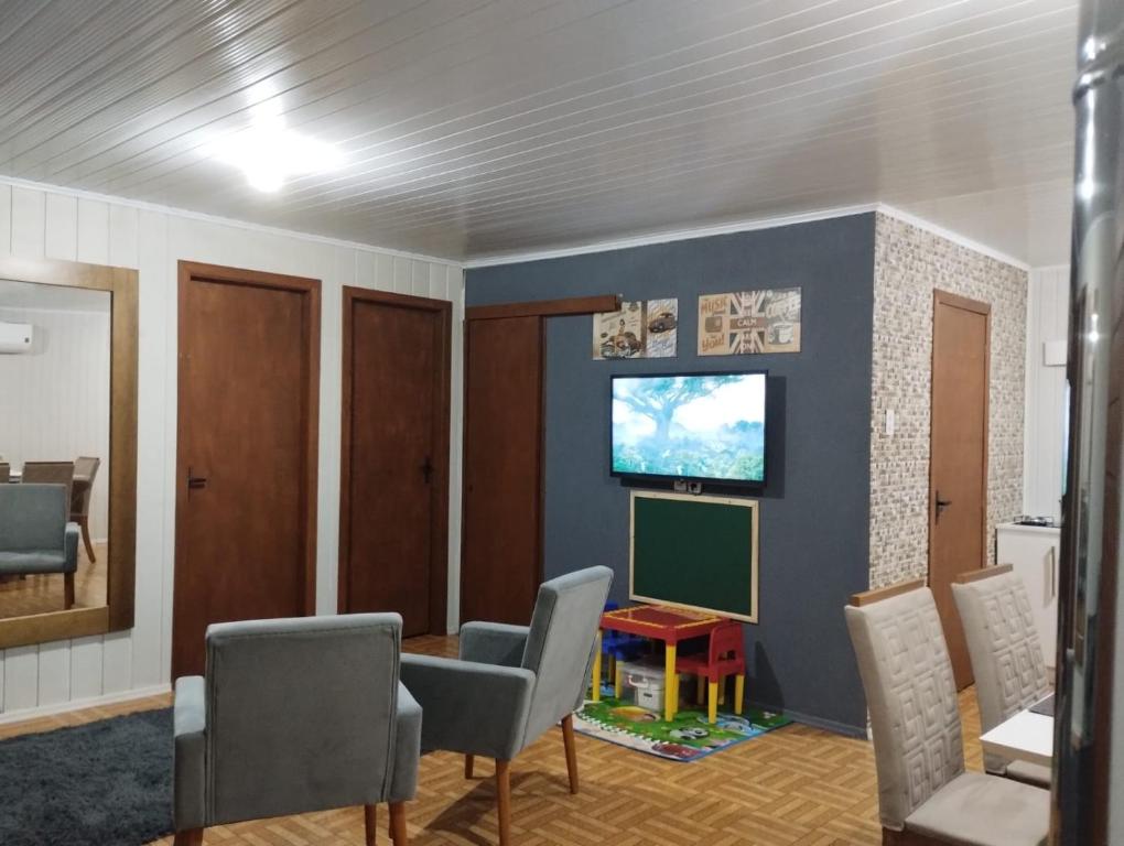 uma sala de espera com cadeiras e uma televisão na parede em Gramado Família em Gramado