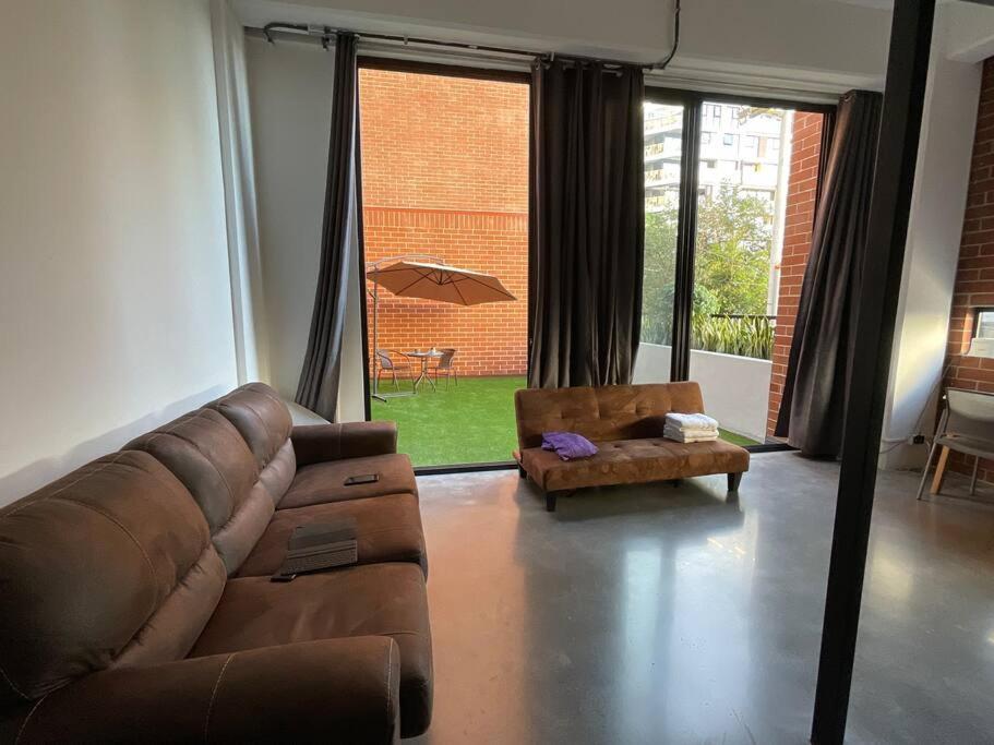 een woonkamer met een bank, een stoel en een paraplu bij Cómodo loft en centro de zona 4 in Guatemala
