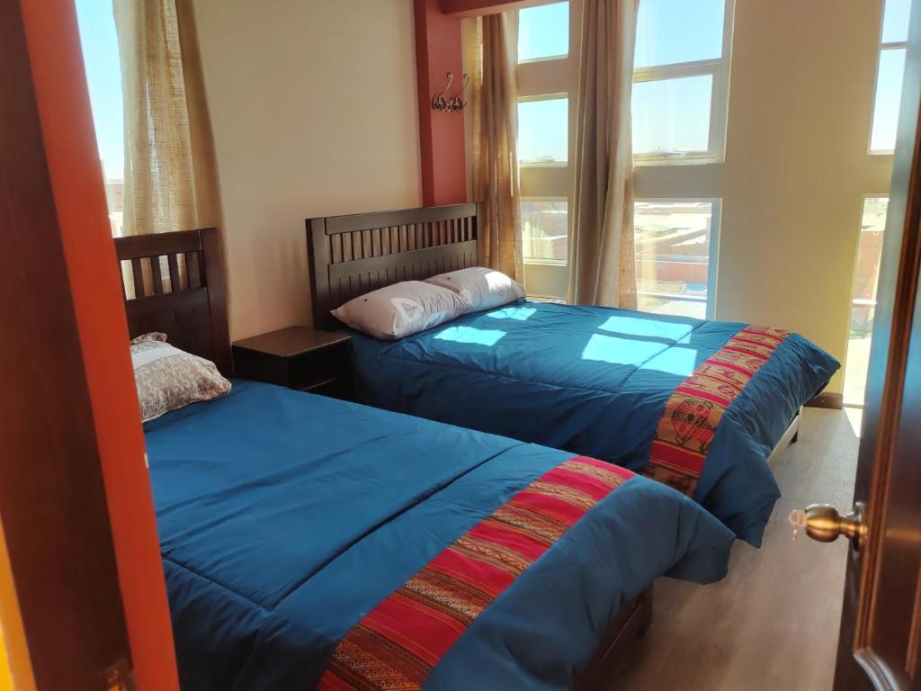 two beds in a room with a window at Uyuni HOSTAL YOKOSO in Uyuni