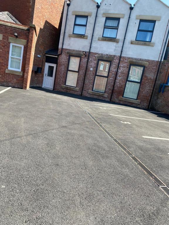 an empty parking lot in front of a brick building at Failsworth Luxury Apartment with Free Parking by Daley Stays in Manchester