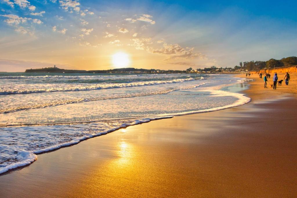 een groep mensen die bij zonsondergang op het strand lopen bij Miramar Beach Home Walk to Beach Trails Restaurants Family Activities in Half Moon Bay